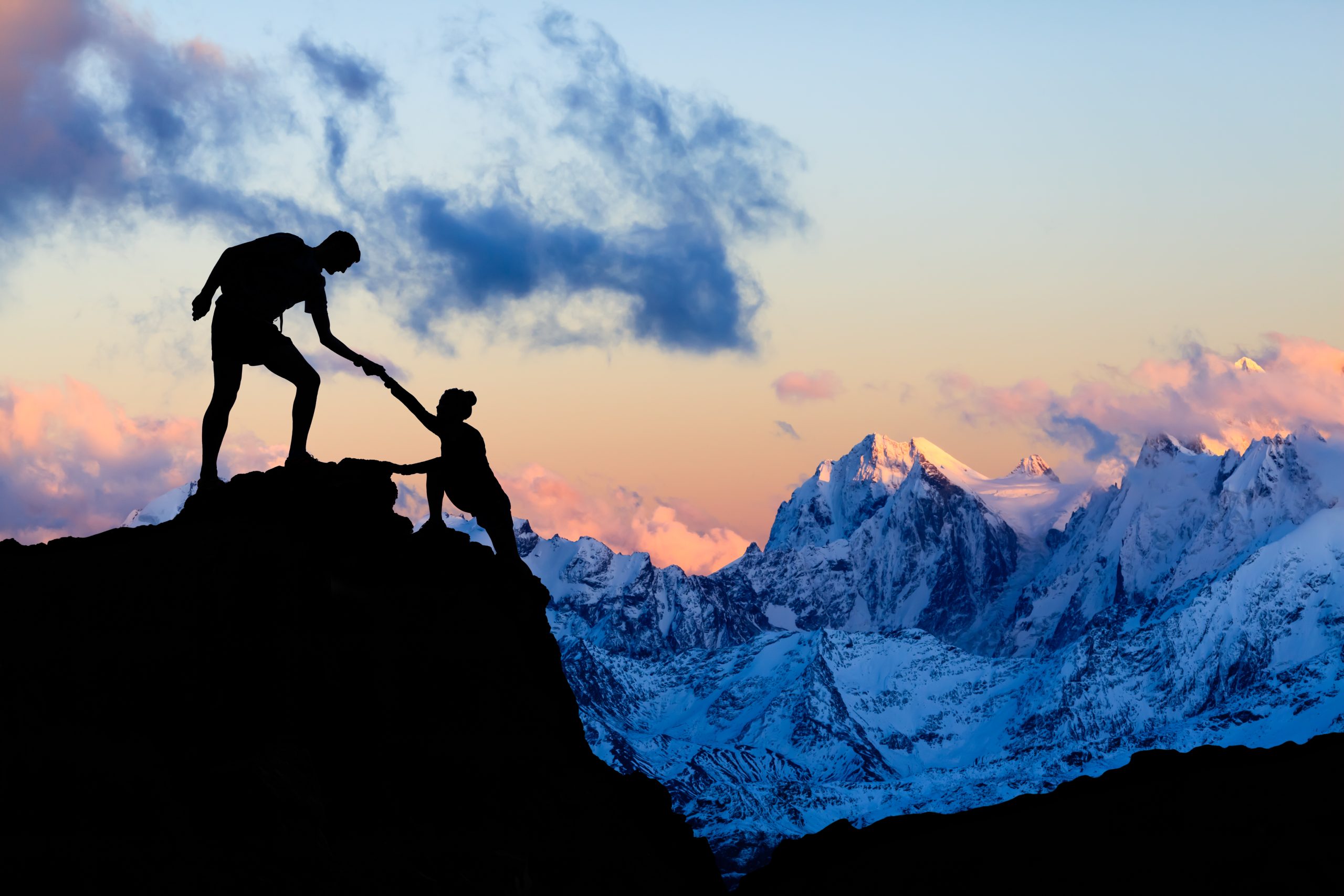 Climbers helping each other to the summit of a mountain